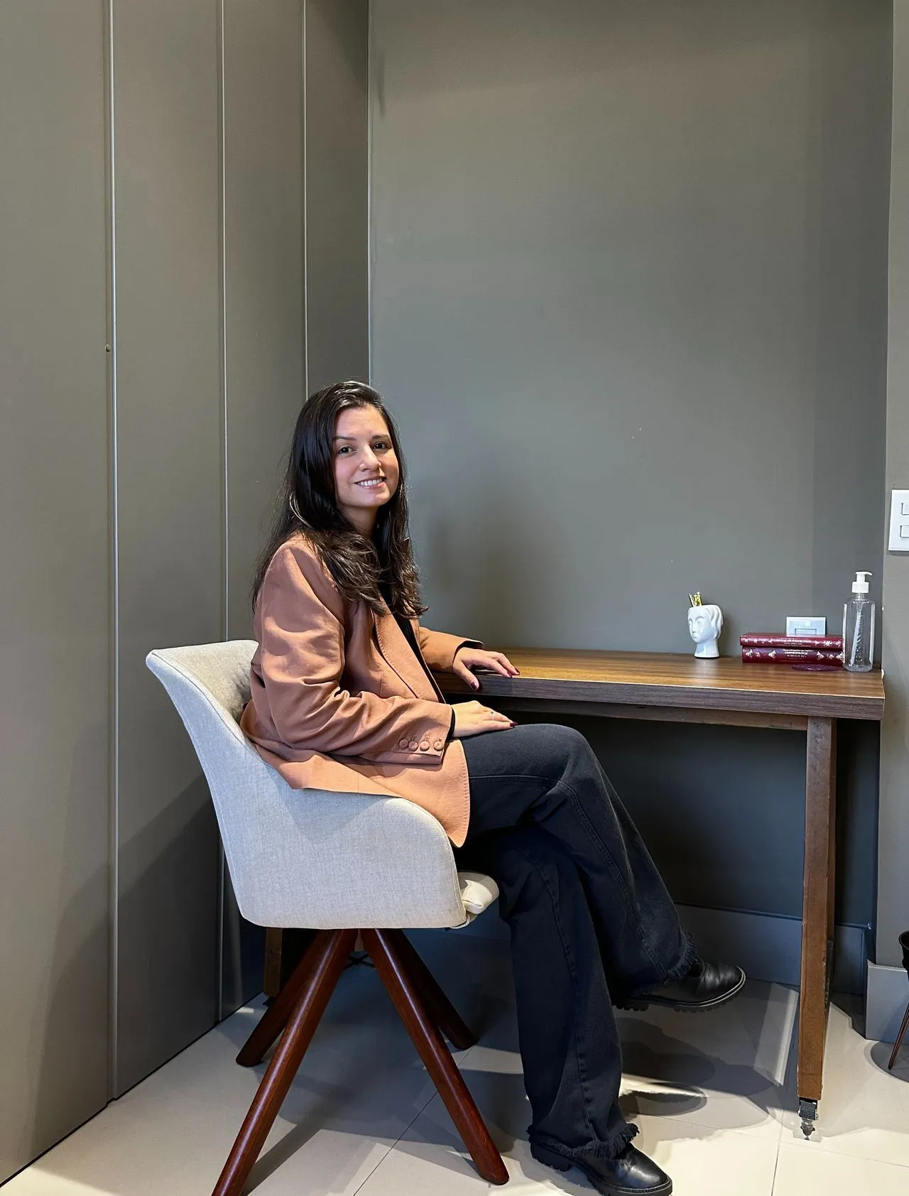 Dra. Caroline Dalla Nora sentada à mesa em seu consultório