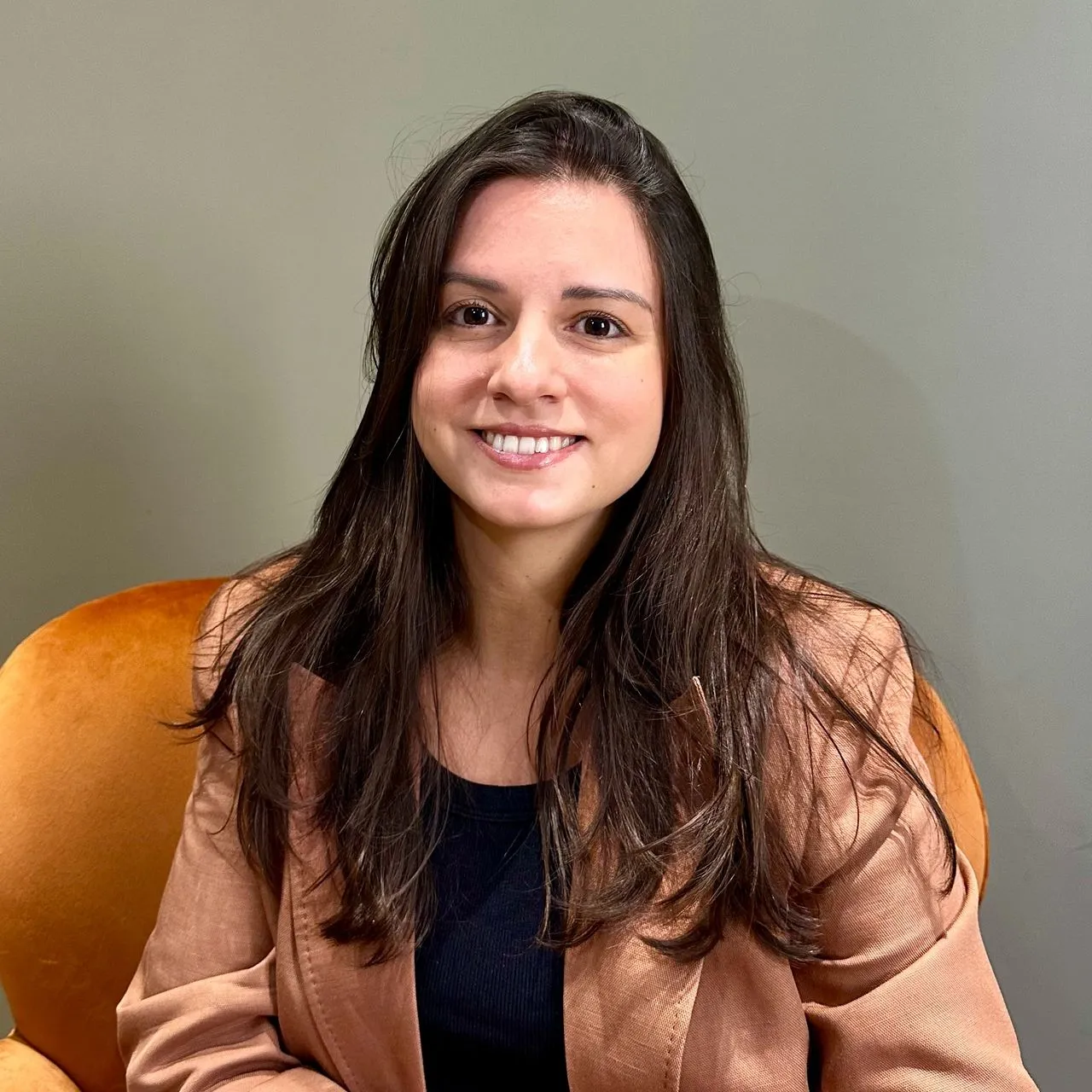 Dra. Caroline Dalla Nora, médica psiquiatra, sorrindo em seu consultório